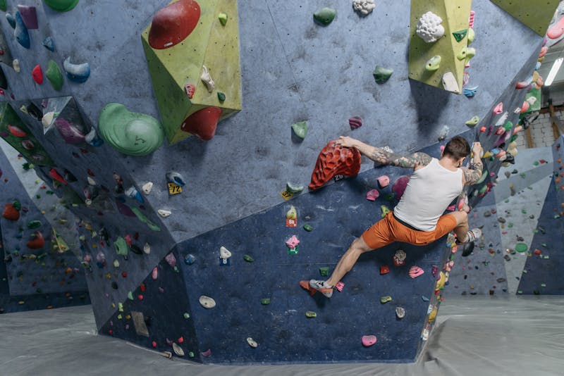 Man climbing on an indoor wall with coloured holds