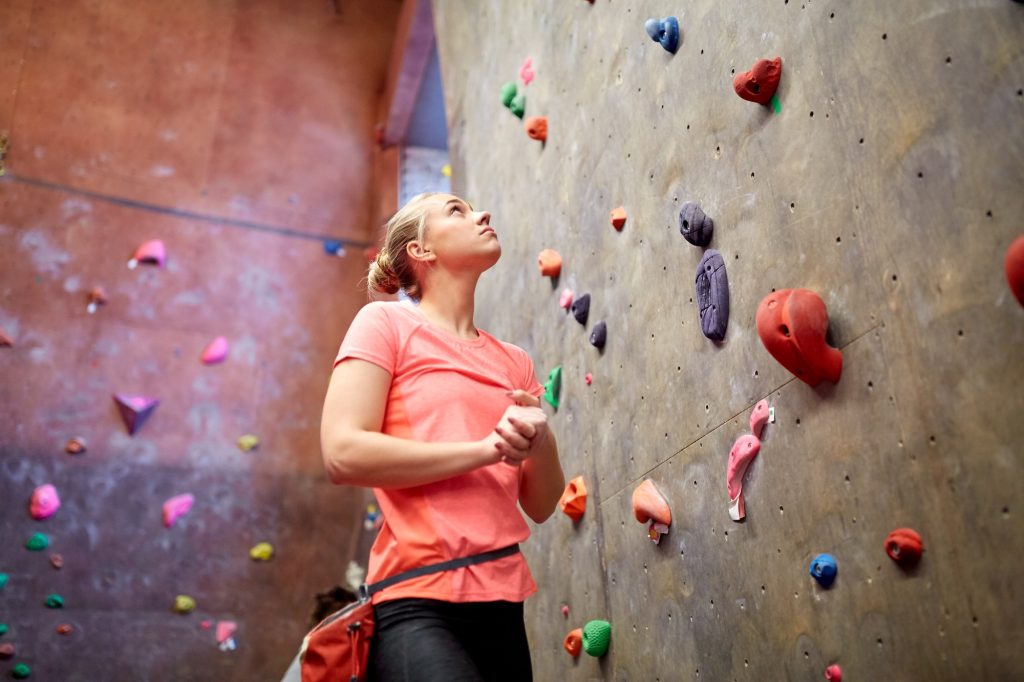 young woman exercising at indoor climbing gym wall